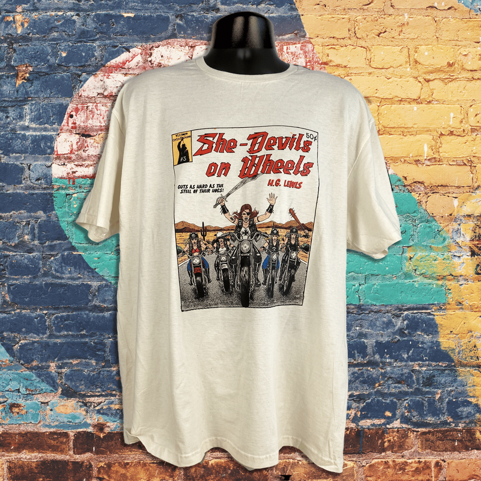 White t-shirt with graphic design of women on motorcycles against a colorful brick wall background