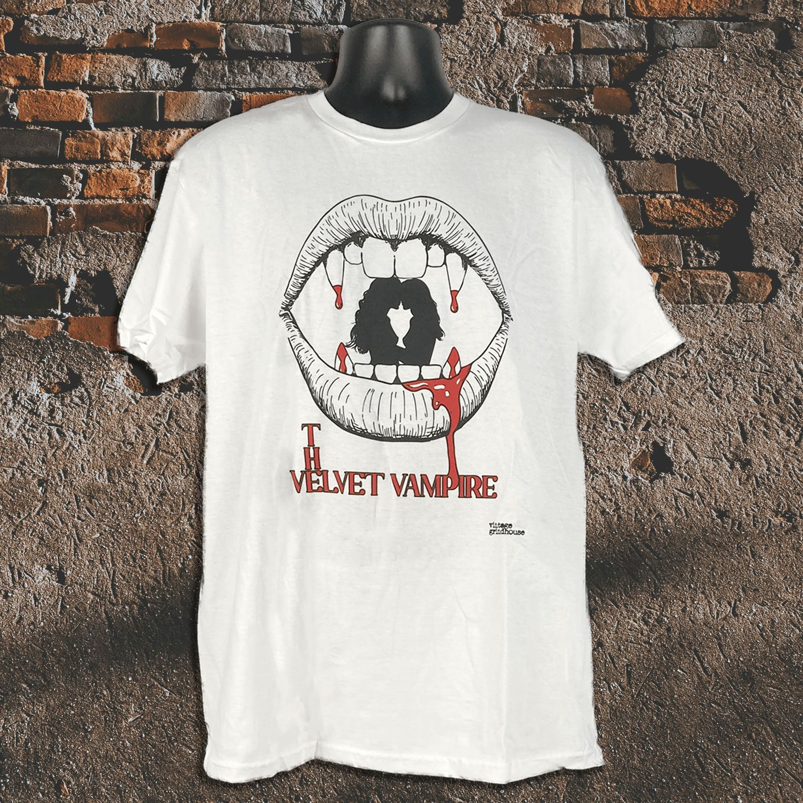 White t-shirt with 'The Velvet Vampire' graphic design on a textured brick wall background