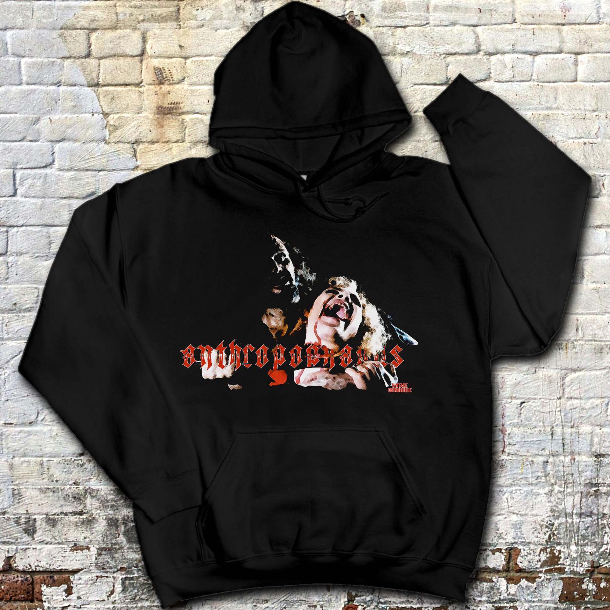Black hoodie with a graphic of a man and woman screaming and red gothic-style text on the front, laid on a brick surface.