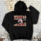 Black hoodie with graphic design on a textured brick wall background