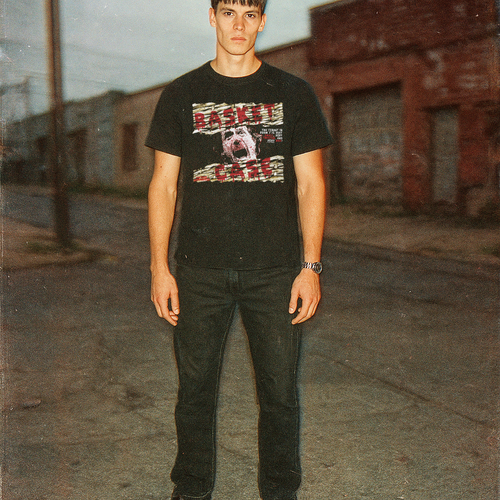Person wearing a black t-shirt with graphic design standing on a street.