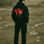 Person wearing a black hoodie with red text and graphics outdoors