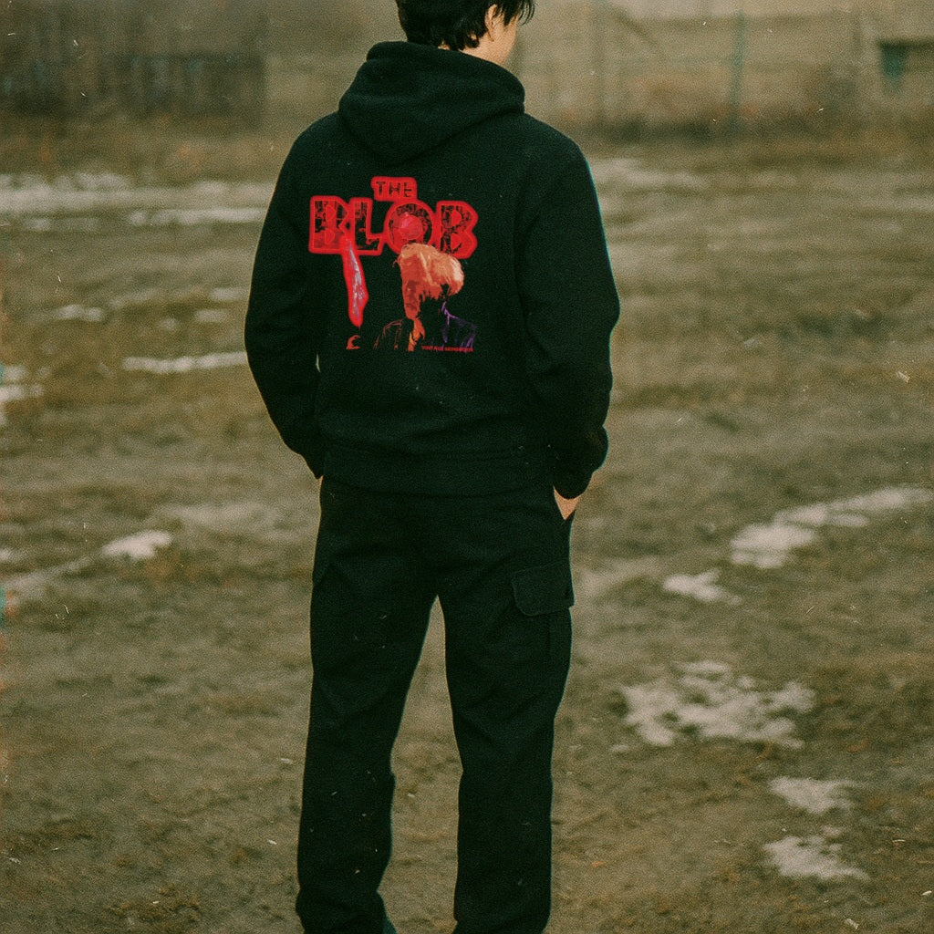 Person wearing a black hoodie with red text and graphics outdoors