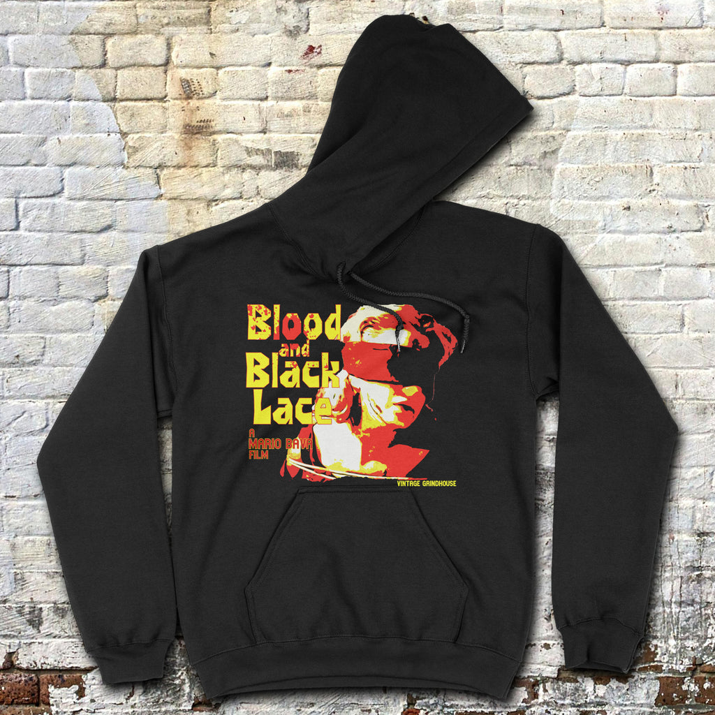 Black Blood and Black Lace hoodie with bold yellow and red vintage film graphic laid flat against brick wall background