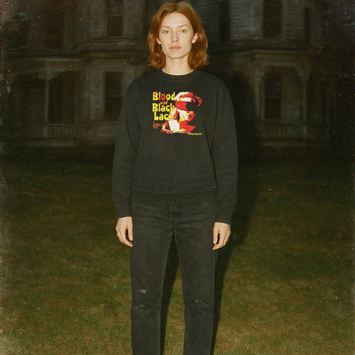 Blood and Black Lace sweatshirt with vivid red and yellow graphic worn by model standing outdoors in dim light