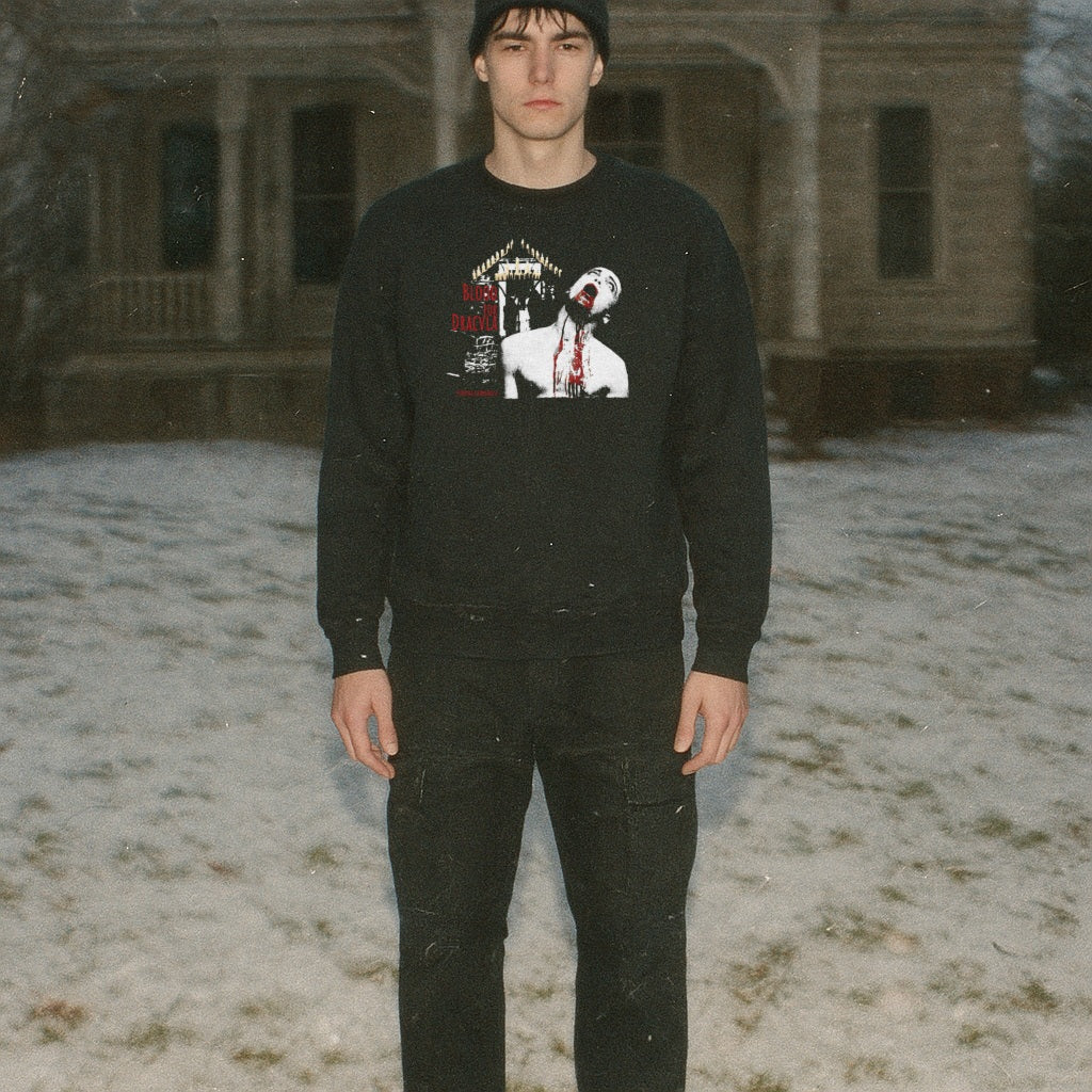 Man wearing Blood for Dracula sweatshirt with graphic of vampire biting neck and dripping blood on black fabric outdoors