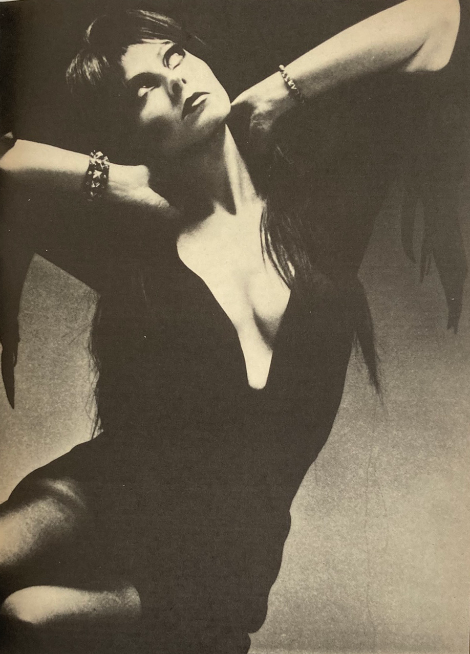 Black and white photo of a woman posing with her hands behind her head.