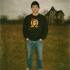 Man standing in field wearing Buio Omega aka Beyond the Darkness sweatshirt with glowing skull and omega symbol graphic