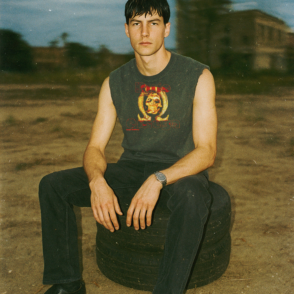 Man sitting on a tire in an outdoor setting with a blurred background