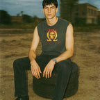 Man sitting on a tire in an outdoor setting with a blurred background