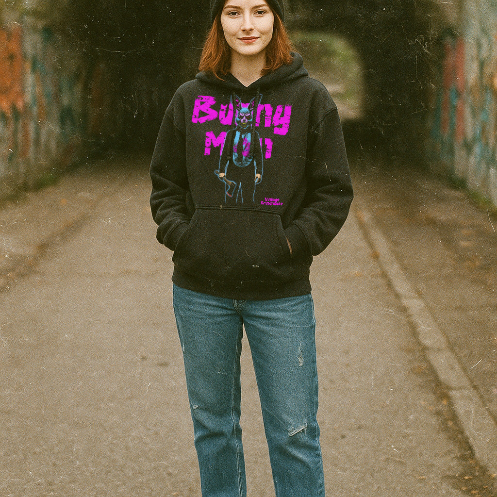 Woman standing outdoors wearing a black Bunnyman hoodie with bright pink text and eerie bunny graphic on front