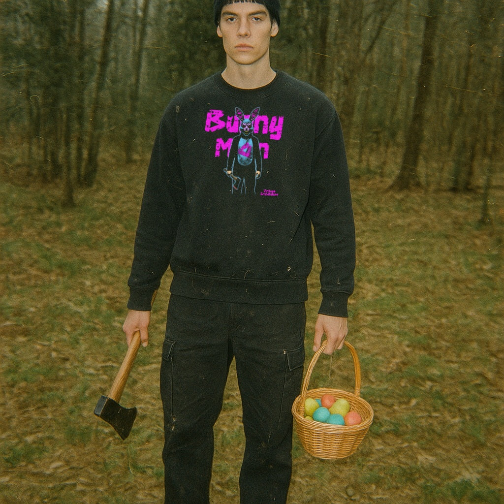 Person wearing Bunny Man Sweatshirt with neon pink text and graphic of a rabbit figure holding a small dog and an axe outdoors