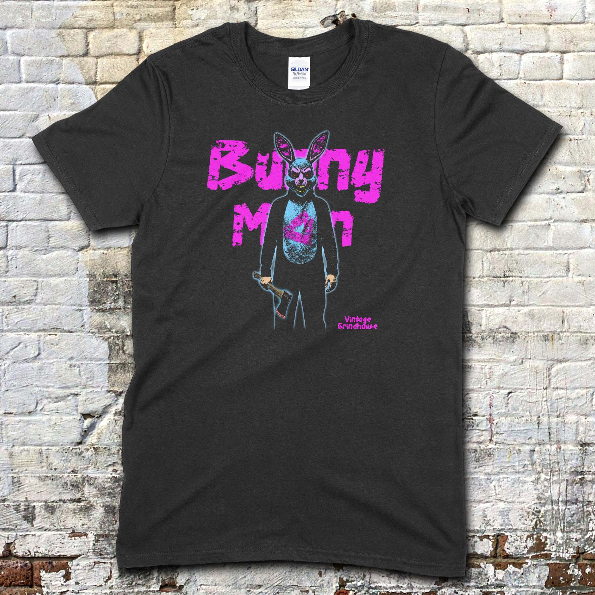 Black t-shirt featuring a graphic of a man in a creepy bunny suit holding a puppet with Bunny Man text in pink on front