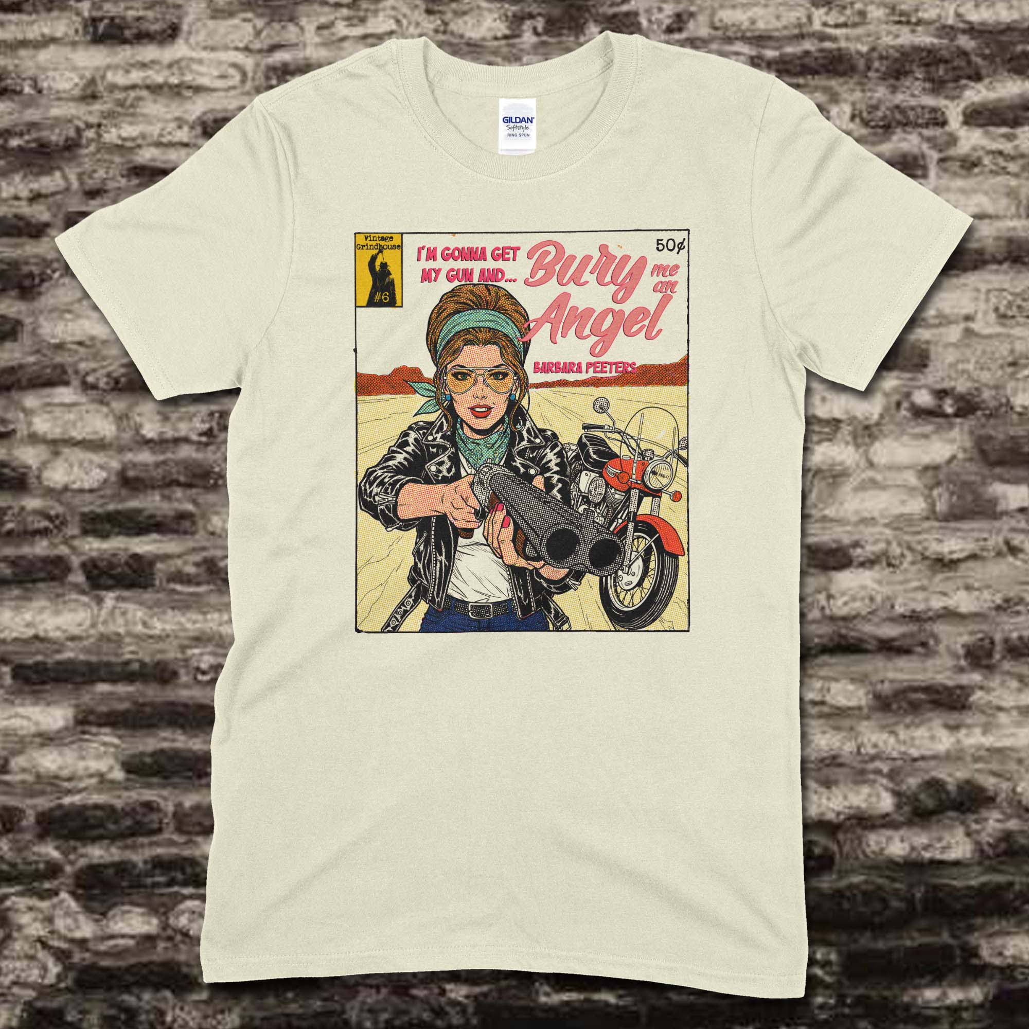 Beige t-shirt featuring a vintage comic style graphic of a woman aiming a shotgun with Bury Me an Angel text on front