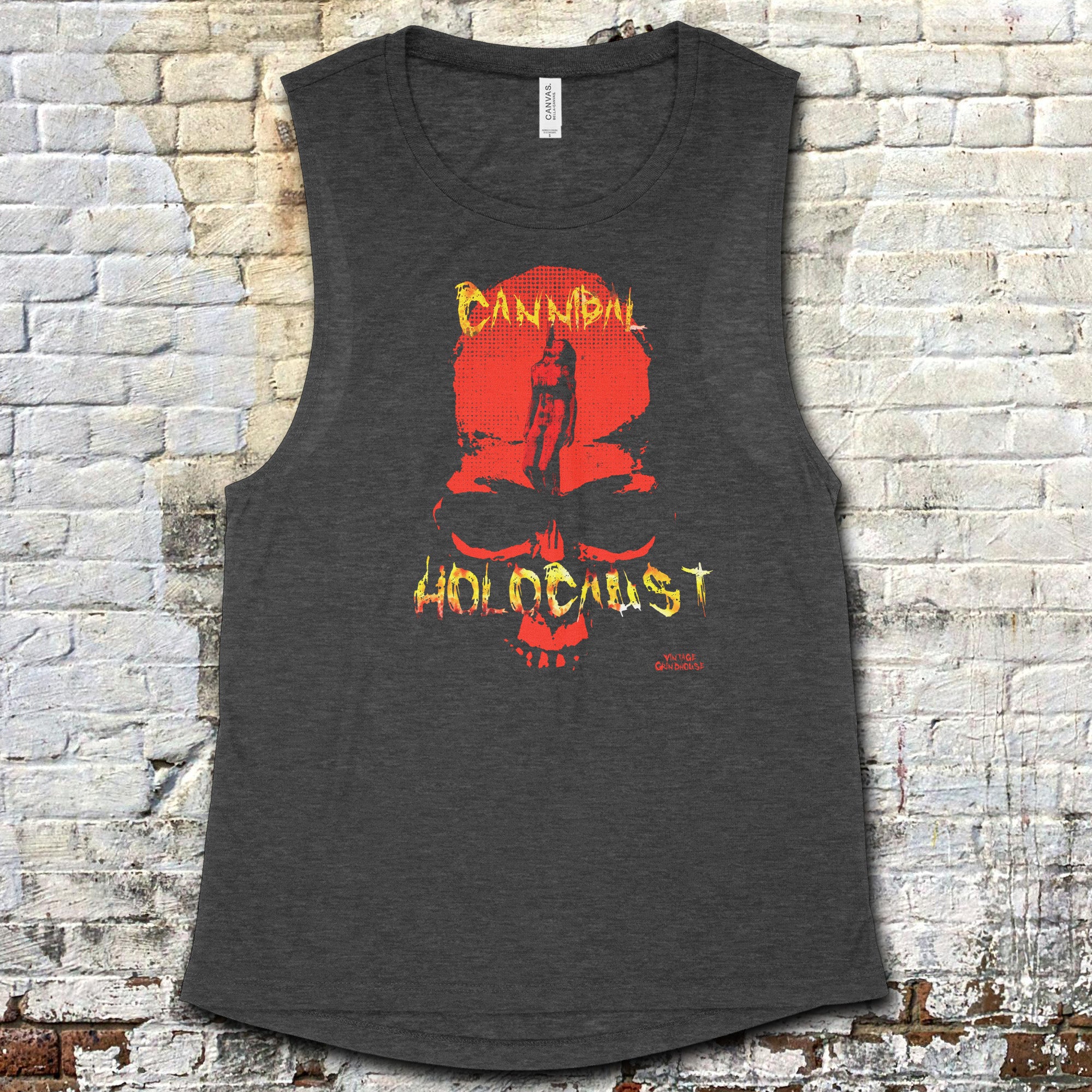 Cannibal Holocaust muscle tank with fiery skull and distressed yellow text on dark gray fabric against brick background