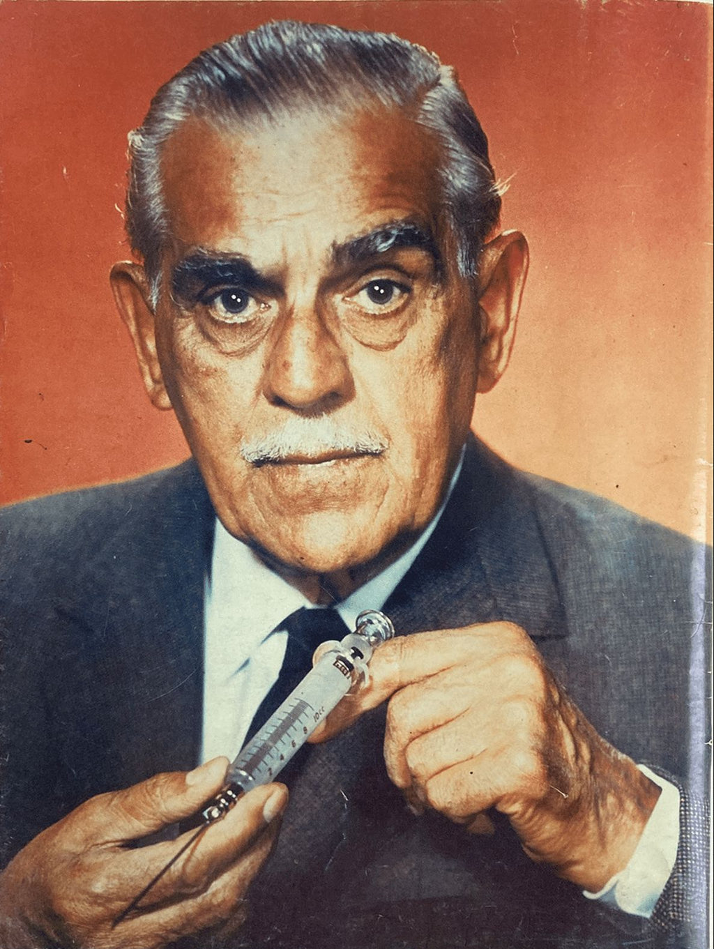 Man holding a syringe against a red background