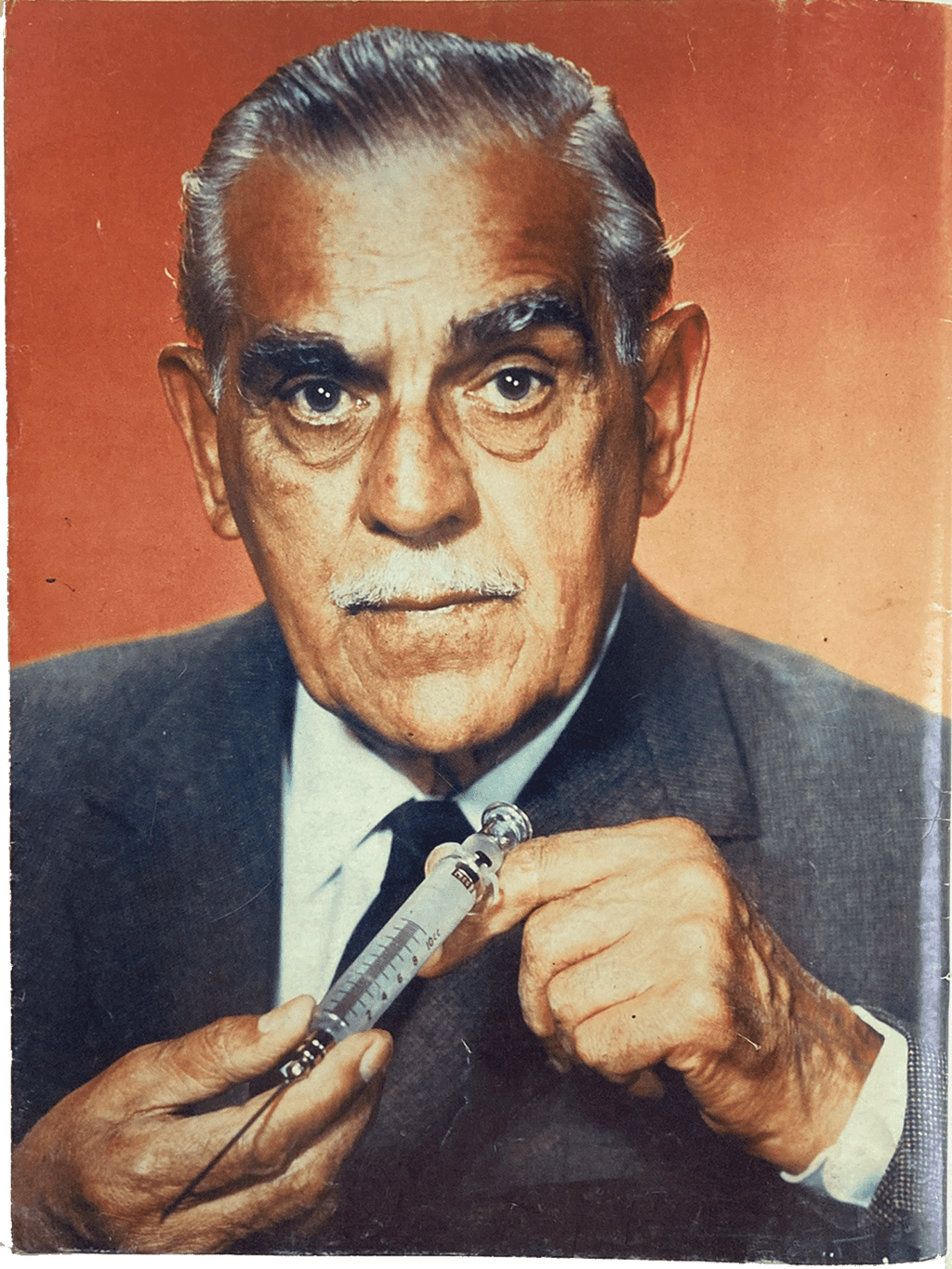 Man holding a syringe against a red background