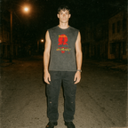 Cannibal Holocaust muscle tank with bold red graphic and distressed yellow text worn by model standing on dark street at night