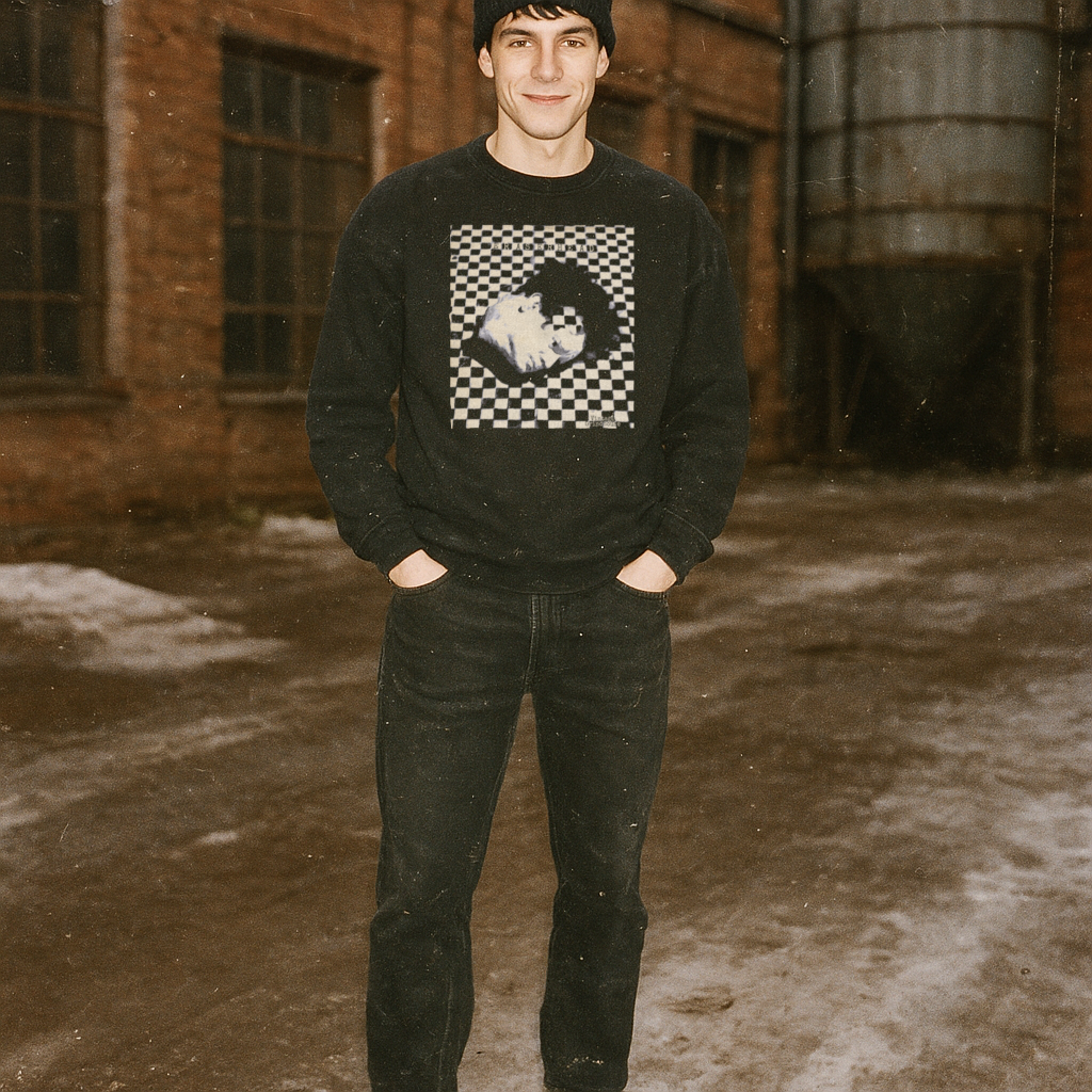 Man wearing Eraserhead sweatshirt with stylized black and white portrait and checkerboard pattern in rustic outdoor setting