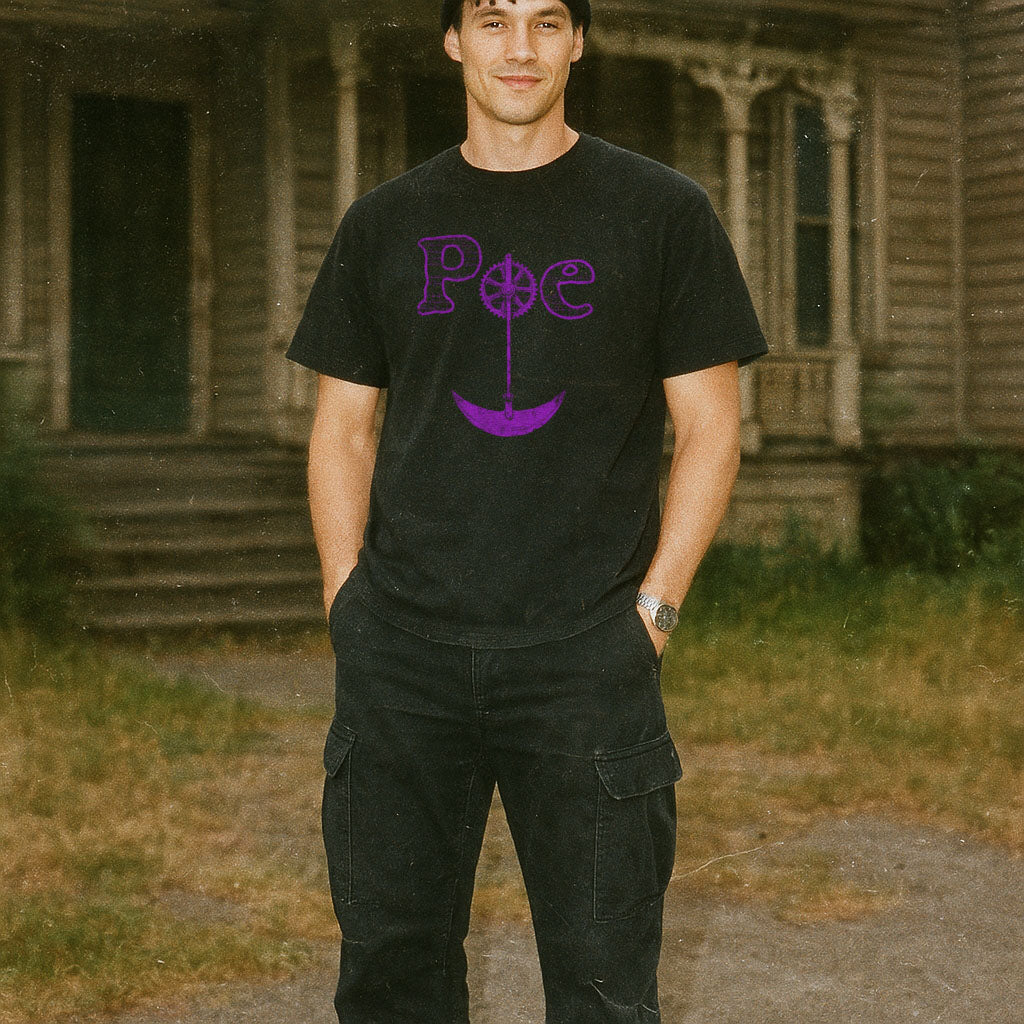 Man wearing black Edgar Allen Poe t-shirt with purple Gothic lettering standing outdoors by old wooden building