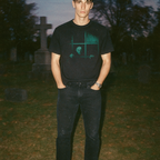 Man wearing Nosferatu: A Symphony of Horror black shirt with eerie vampire graphic in nighttime graveyard setting