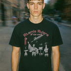 Young man wearing Atomic Rulers of the World t-shirt featuring retro sci-fi characters and spaceship design on black shirt.