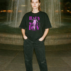 Person wearing a black t-shirt with graphic design in front of a fountain at night.