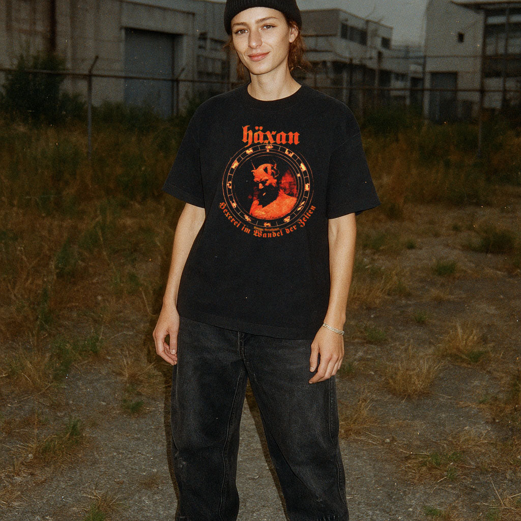 Person wearing a black t-shirt with a graphic design in an outdoor setting