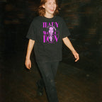 Person wearing black Mary Woronov - Legendary Lady of Grindhouse Cinema t-shirt with purple text and image walking outdoors at night