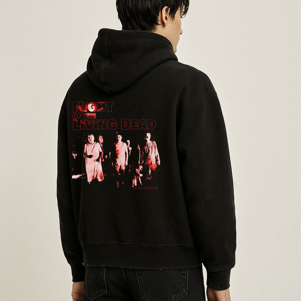 Person wearing a black hoodie with a graphic design on the back against a beige background