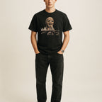 Black t-shirt featuring Zombi 2 graphic with a decayed zombie head looming over a city skyline and bridge scene