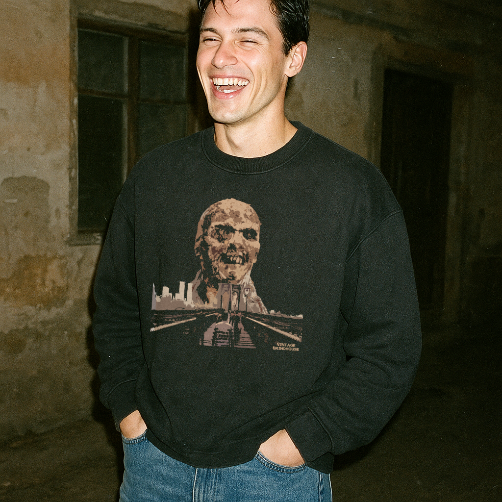 Man wearing Zombi 2 sweatshirt with vintage horror graphic of zombie head and cityscape on black fabric outdoors at night