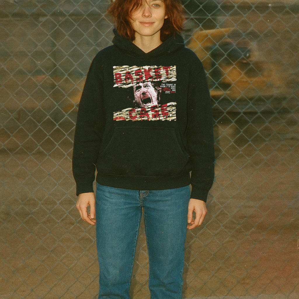 Person wearing a black hoodie with graphic design in front of a chain-link fence.