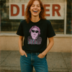 Young woman smiling outdoors wearing Doris Wishman t-shirt Design 2 featuring retro woman with sunglasses and leopard print accents.