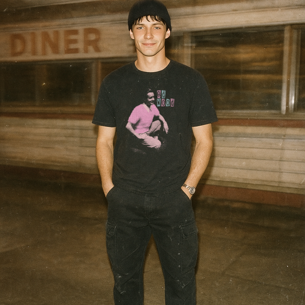 Young man in black beanie wearing an Ed Wood t-shirt with vintage style graphic standing by a diner at night