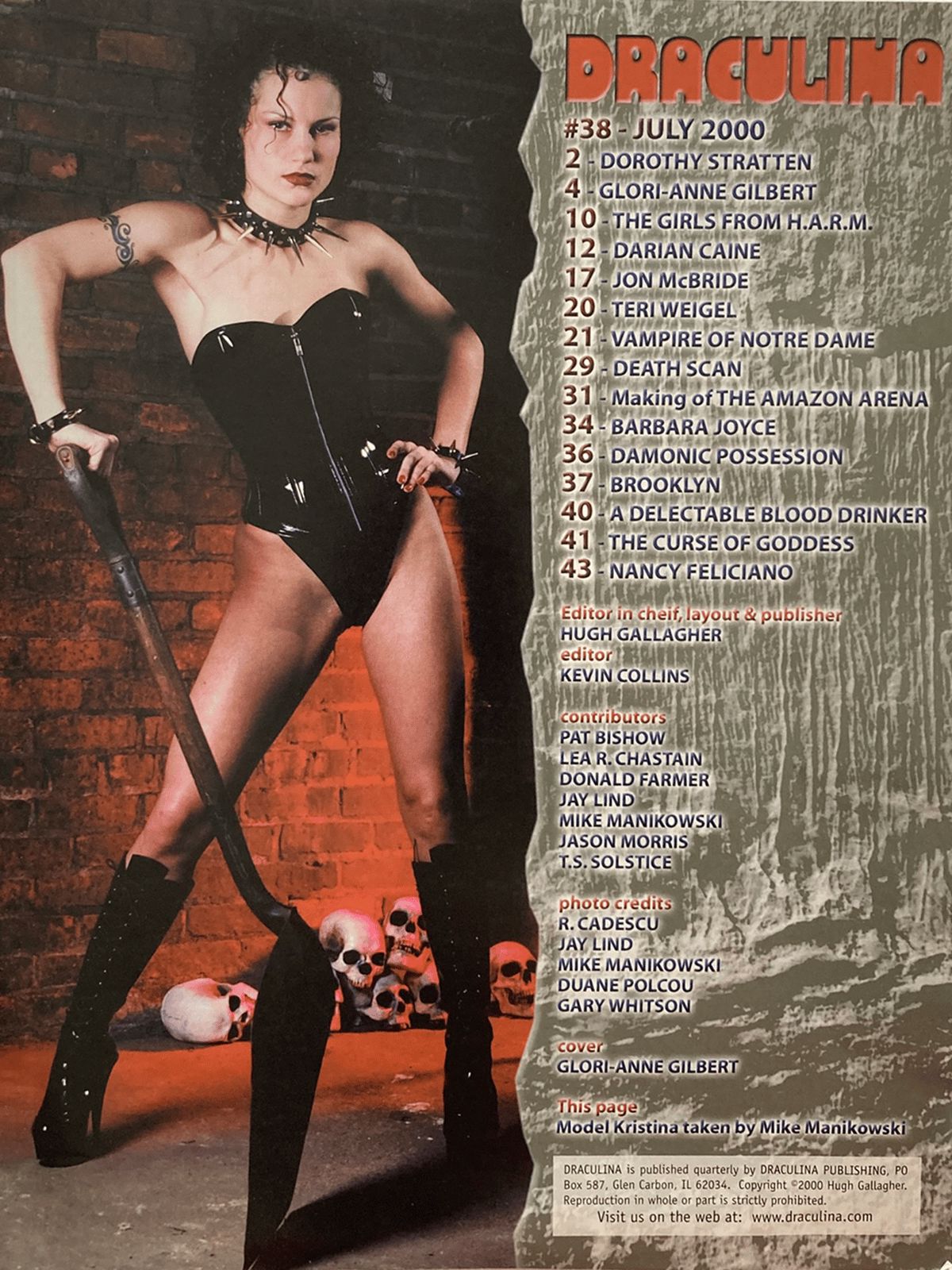 Magazine cover featuring a woman in a black outfit with a staff, against a brick wall background.