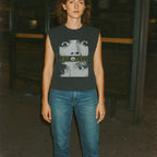 Person wearing a sleeveless shirt with graphic design in a dark setting
