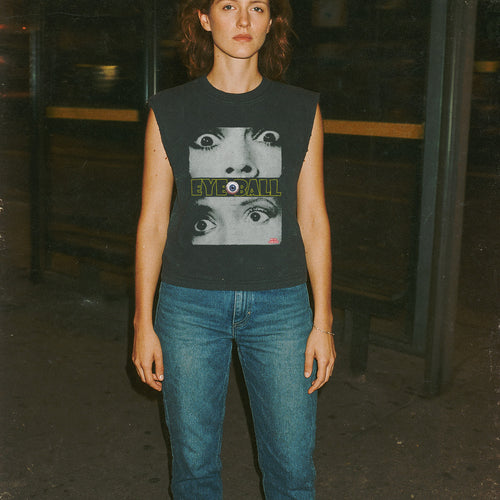 Person wearing a sleeveless shirt with graphic design in a dark setting