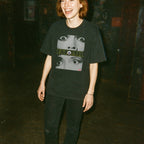 Person wearing a black t-shirt with graphic design, standing against a dark background