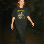 Person wearing a black t-shirt with a graphic design on a dark background