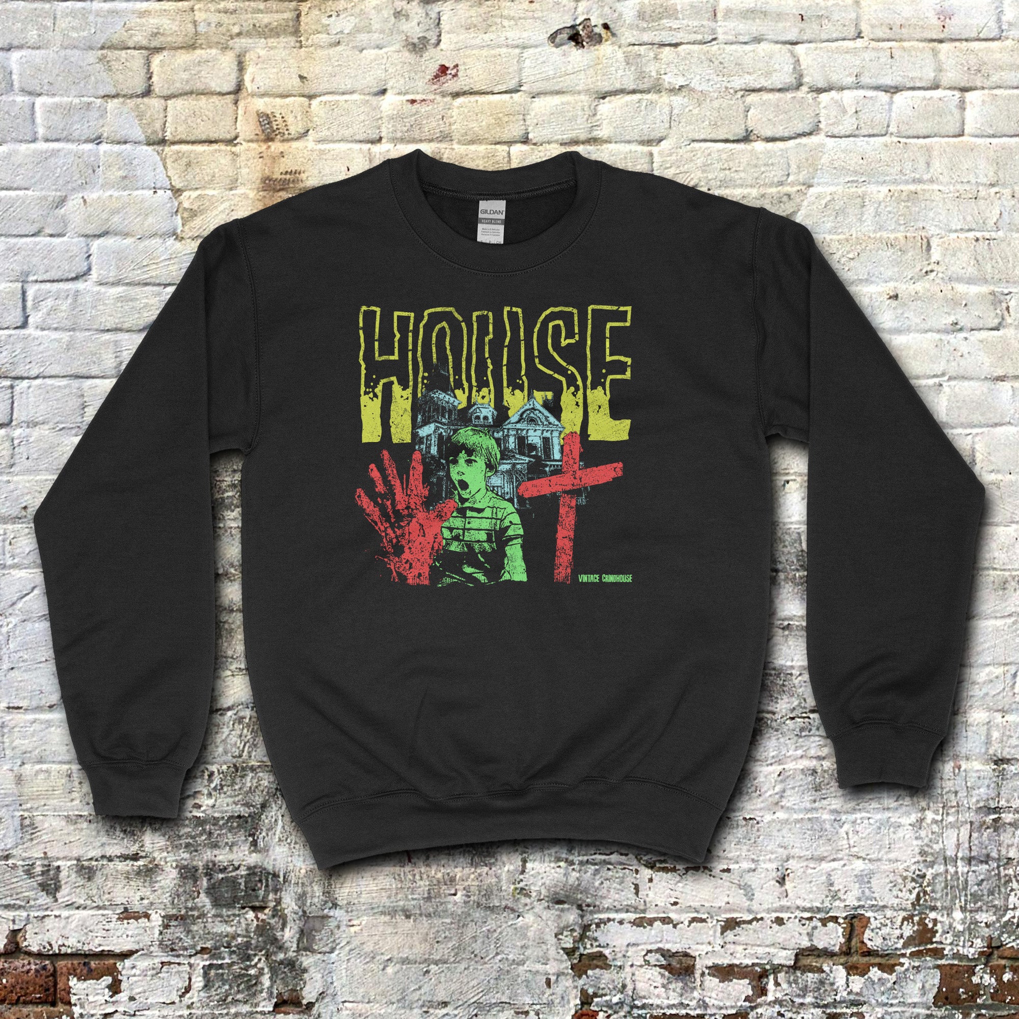 House sweatshirt featuring bold distressed yellow lettering, eerie green child, red handprint, cross, and haunted house graphic on black fabric