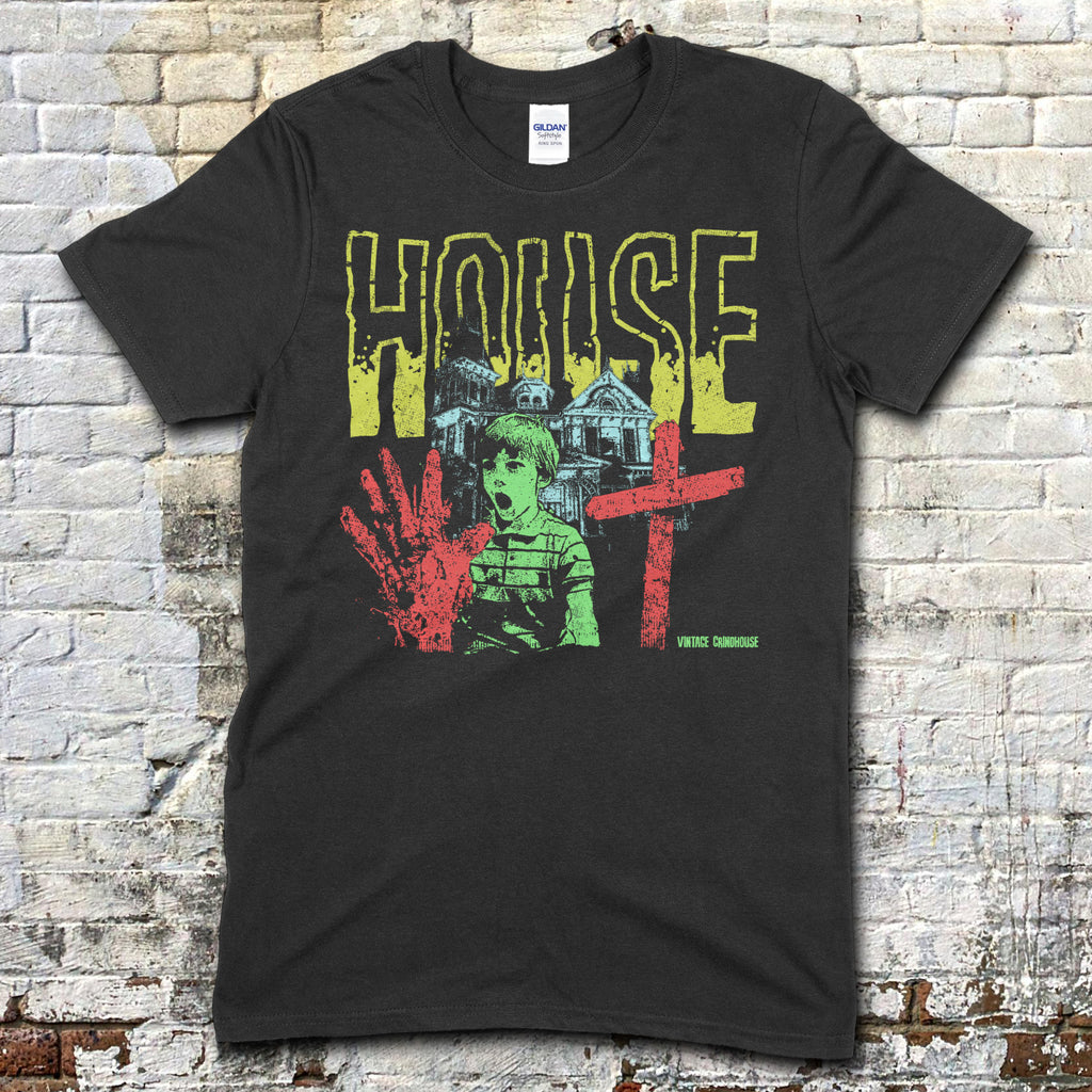 Black t-shirt featuring a distressed yellow House text with a haunted house, boy, bloody handprint, and red cross graphic on front