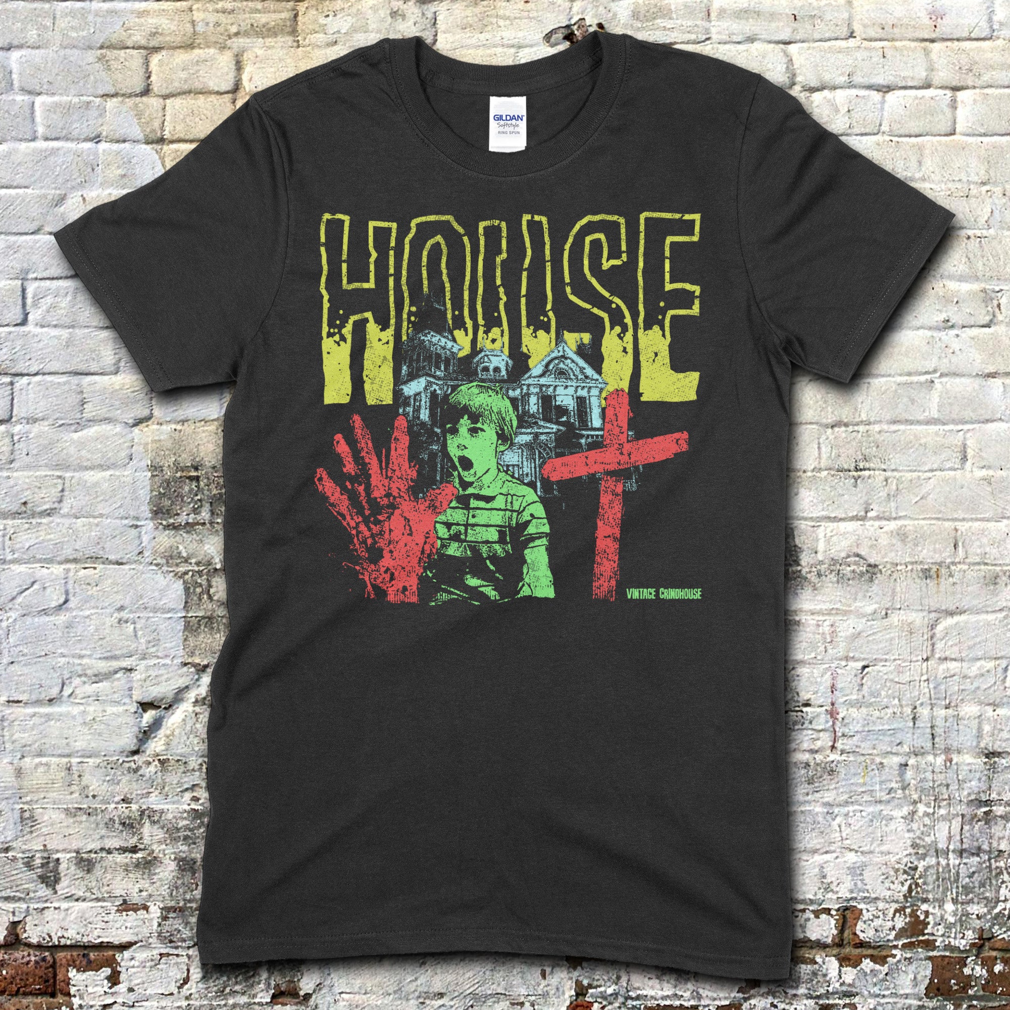 Black t-shirt featuring a distressed yellow House text with a haunted house, boy, bloody handprint, and red cross graphic on front