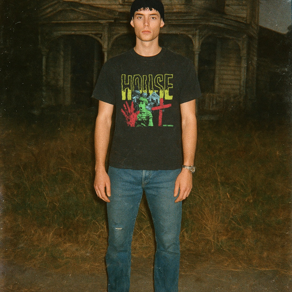 Person wearing a black t-shirt with colorful graphic design in front of an old building.