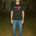 Person wearing a black t-shirt with a graphic design in an outdoor setting