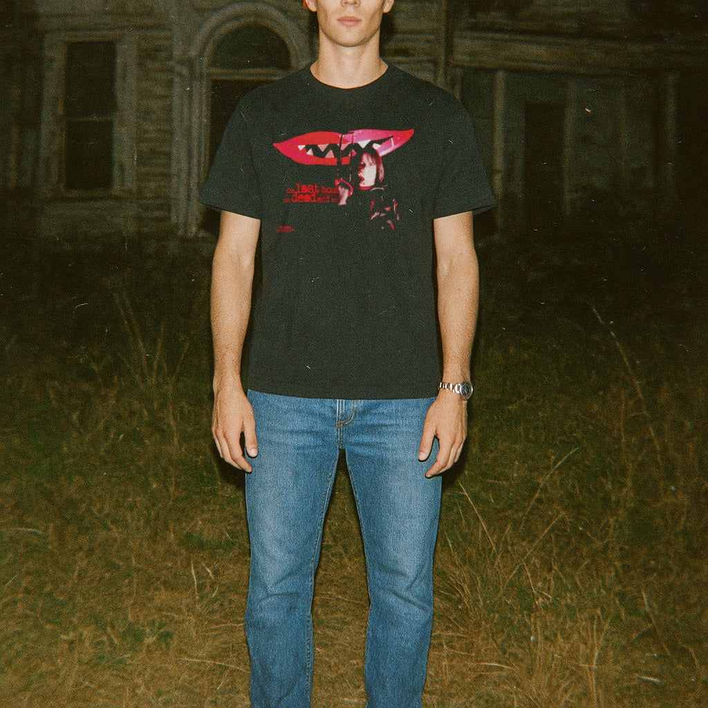 Person wearing a black t-shirt with a graphic design in an outdoor setting
