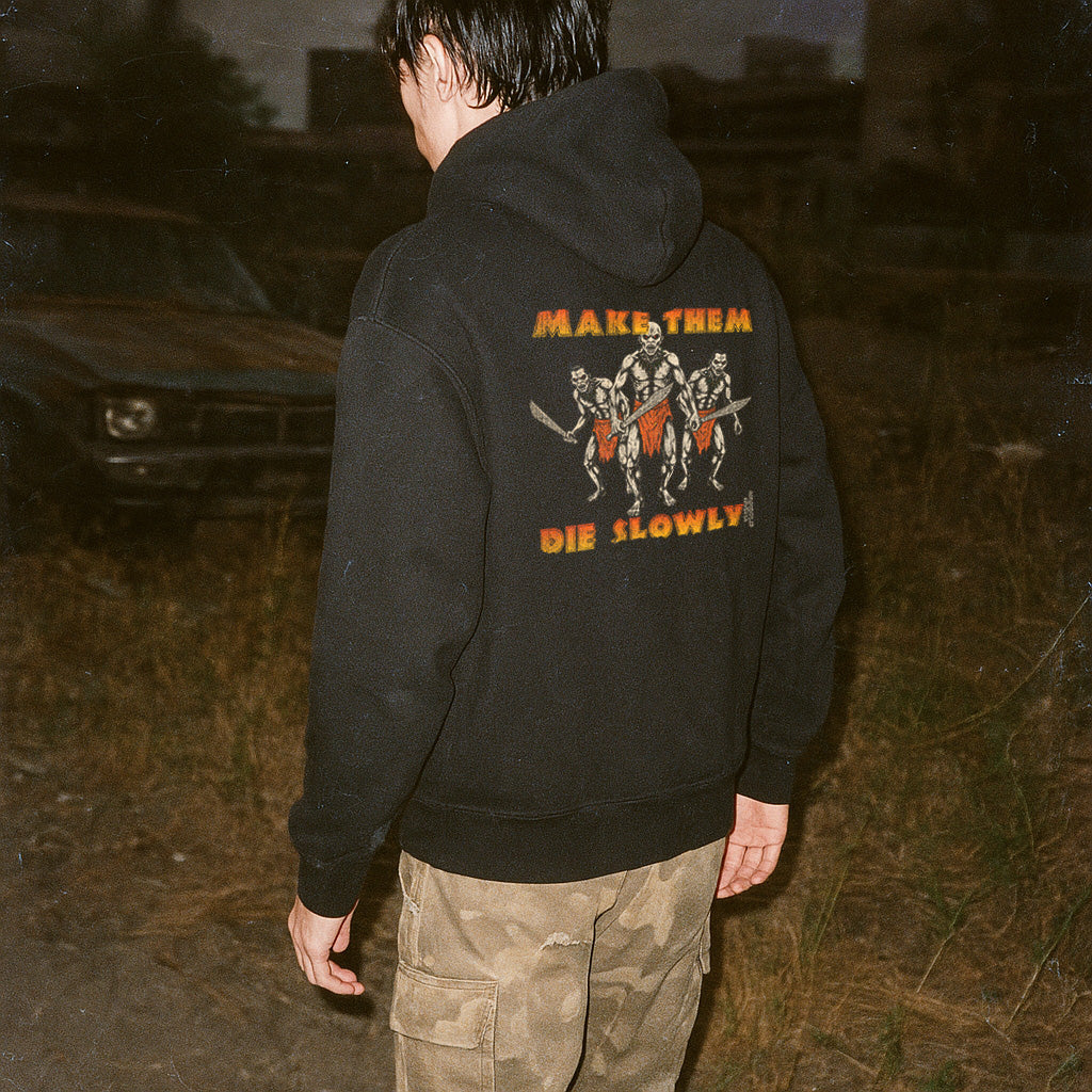 Person wearing a black hoodie with a graphic design on the back, standing outdoors.