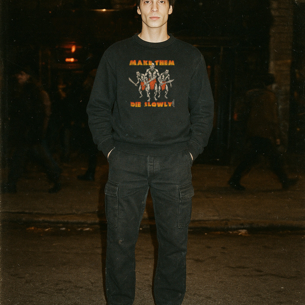 Person wearing a black sweatshirt with graphic design and text, standing in a dark, possibly urban setting.
