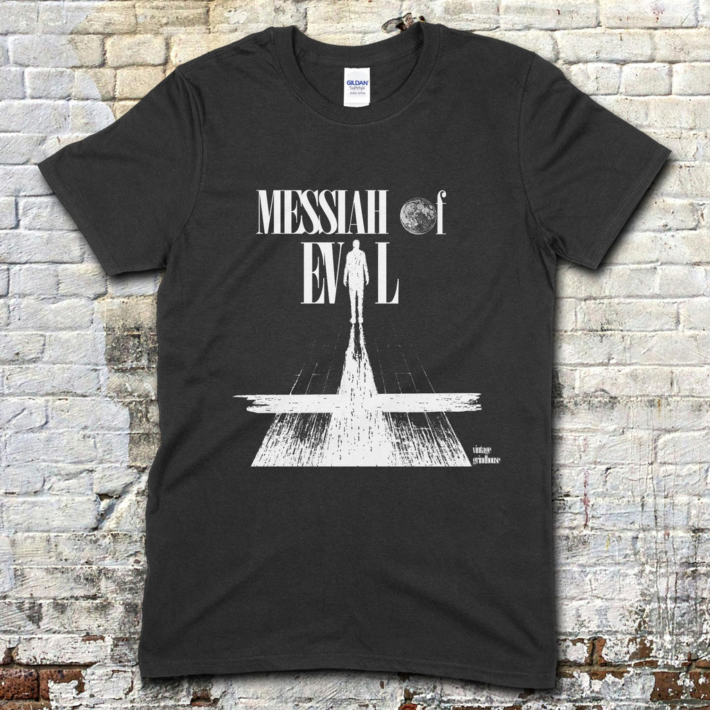 Black t-shirt with white graphic design featuring a silhouette and text, against a brick wall background.