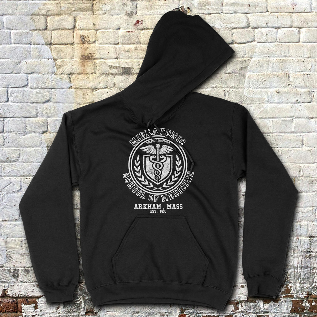 Black hoodie with a graphic design on the back against a brick wall.